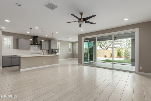 unfurnished living room with a ceiling fan, visible vents, light wood finished floors, baseboards, and recessed lighting