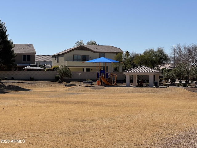 back of property featuring a gazebo, playground community, fence, and stucco siding