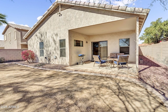 rear view of house featuring a fenced backyard, outdoor lounge area, a tiled roof, stucco siding, and a patio area