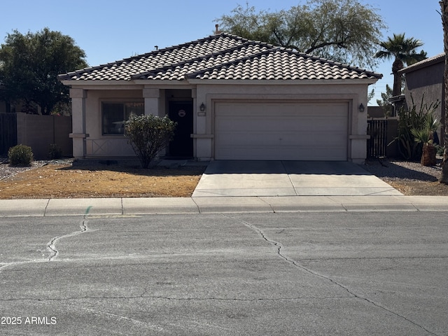 view of front of home featuring a garage, concrete driveway, a tile roof, fence, and stucco siding