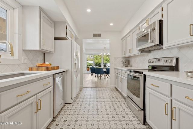 kitchen featuring backsplash, white cabinets, sink, appliances with stainless steel finishes, and a chandelier