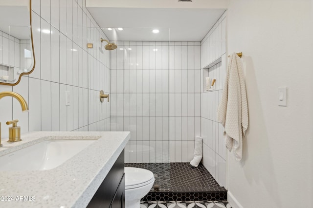 bathroom with vanity, toilet, and a tile shower