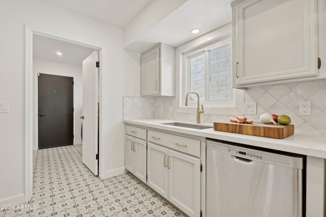 kitchen with decorative backsplash, white cabinetry, sink, and stainless steel dishwasher