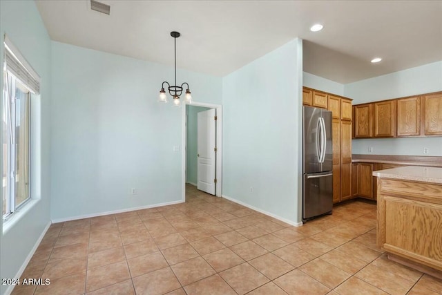 kitchen featuring pendant lighting, a notable chandelier, stainless steel fridge, and a wealth of natural light