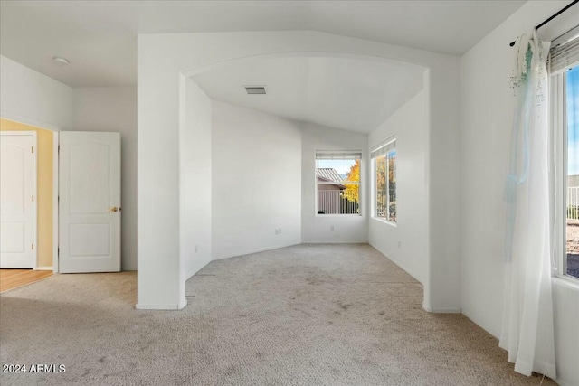 unfurnished room featuring light carpet and vaulted ceiling