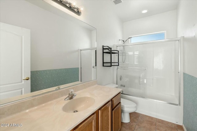 full bathroom featuring tile patterned floors, toilet, combined bath / shower with glass door, and vanity