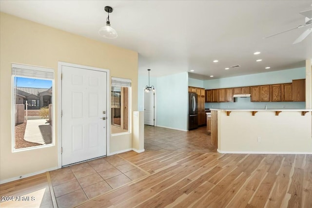 kitchen featuring a kitchen breakfast bar, light hardwood / wood-style floors, stainless steel refrigerator, and pendant lighting