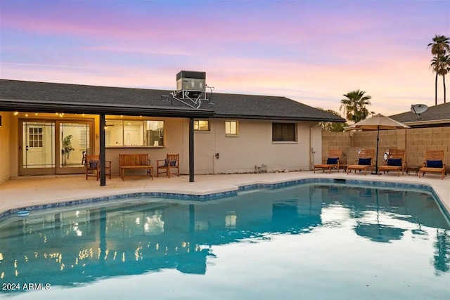 pool at dusk featuring a patio