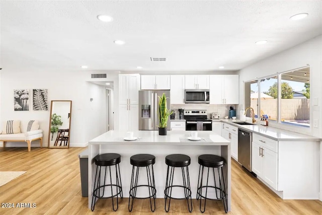 kitchen with a center island, light hardwood / wood-style flooring, white cabinets, and appliances with stainless steel finishes