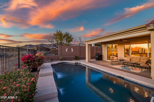 pool at dusk with a patio, outdoor lounge area, a fenced backyard, and a fenced in pool