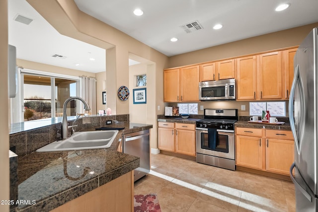 kitchen with light brown cabinets, visible vents, stainless steel appliances, and a sink