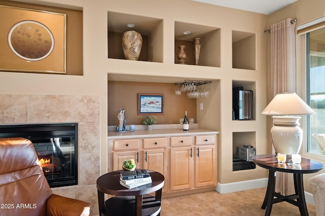 bar featuring a fireplace, a dry bar, light tile patterned floors, plenty of natural light, and baseboards