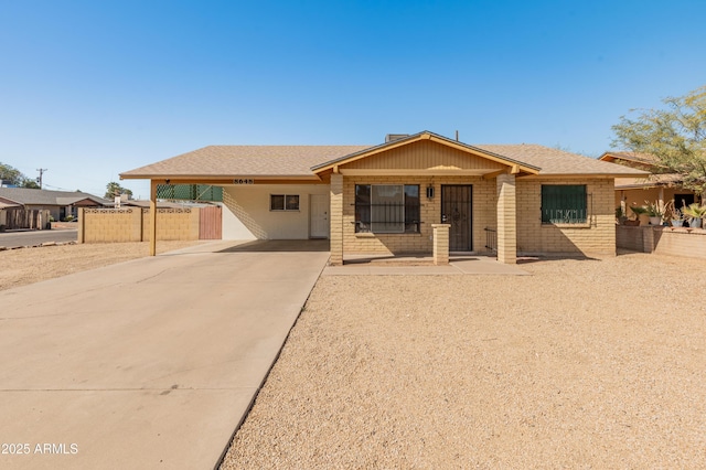 single story home with driveway, brick siding, fence, and an attached carport