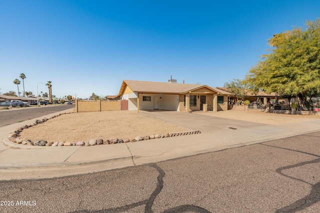 ranch-style house featuring concrete driveway and fence