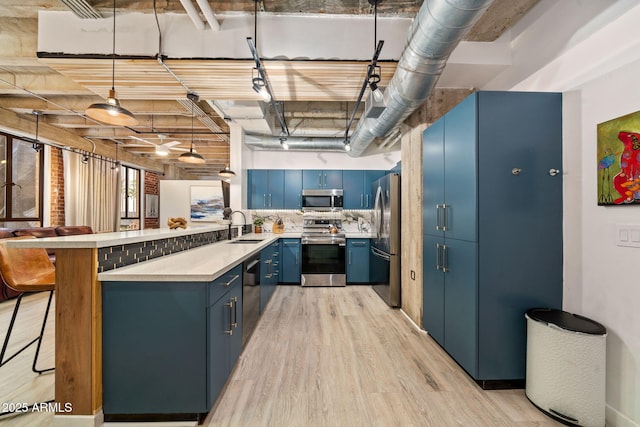 114 W Adams St Unit 202, Phoenix, AZ 85003 - kitchen featuring appliances with stainless steel finishes, blue cabinetry, a peninsula, light wood-style floors, and a kitchen breakfast bar