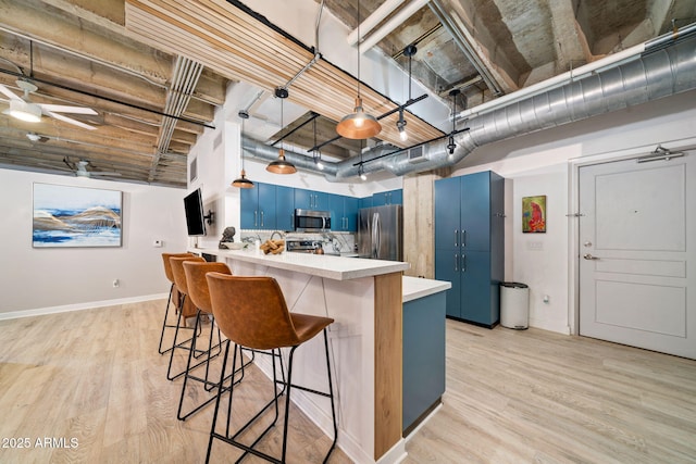 114 W Adams St Unit 202, Phoenix, AZ 85003 - kitchen with blue cabinetry, stainless steel appliances, light countertops, a breakfast bar, and a peninsula