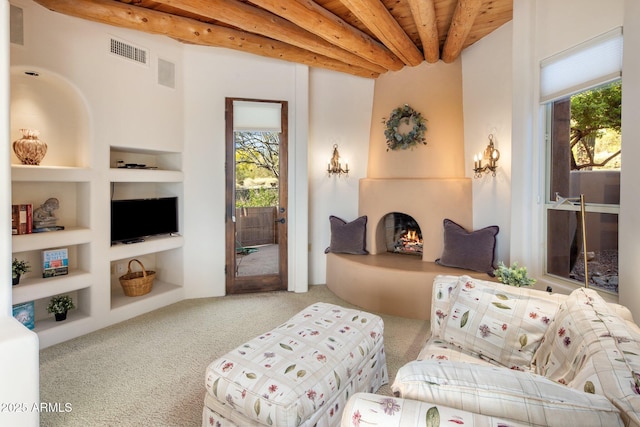 6001 E Restin Rd, Cave Creek, AZ 85331 - living room with carpet flooring, visible vents, built in shelves, beamed ceiling, and a large fireplace