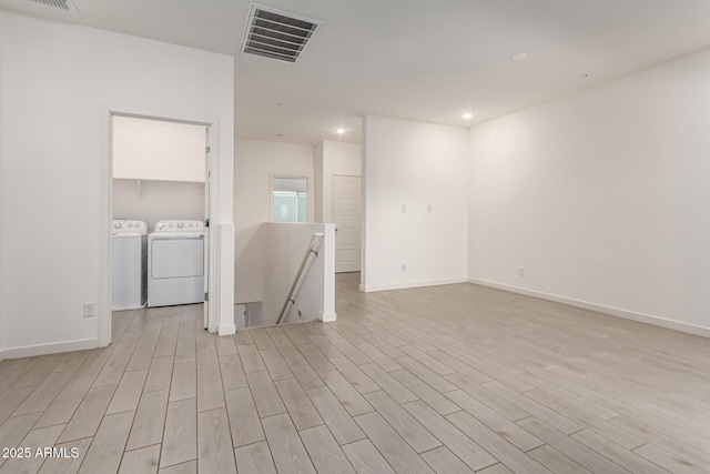 empty room featuring washing machine and dryer and light wood-type flooring