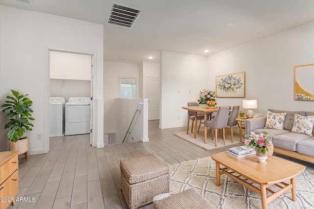 living room with washer and clothes dryer and light hardwood / wood-style floors