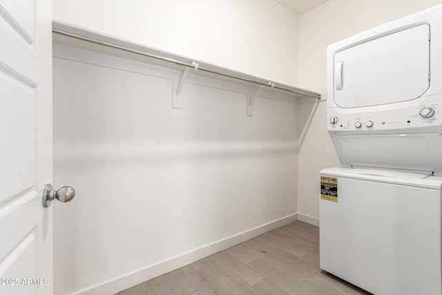 laundry room featuring light hardwood / wood-style floors and stacked washing maching and dryer