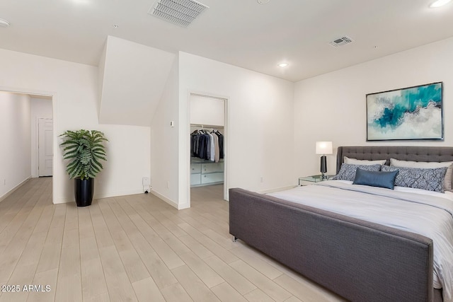 bedroom with a spacious closet and light hardwood / wood-style flooring