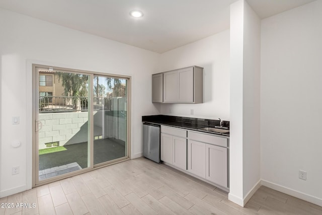 kitchen with gray cabinets, dishwasher, sink, and light wood-type flooring