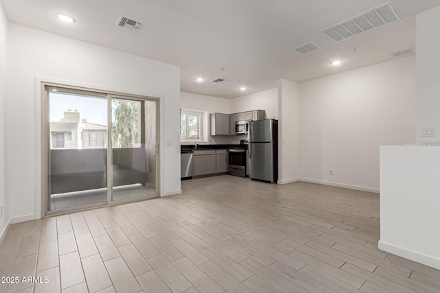 kitchen with stainless steel appliances, gray cabinets, and light hardwood / wood-style flooring