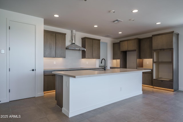 7956 W Griswold Rd, Peoria, AZ 85345 - kitchen featuring wall chimney range hood, a sink, an island with sink, backsplash, and dark brown cabinets