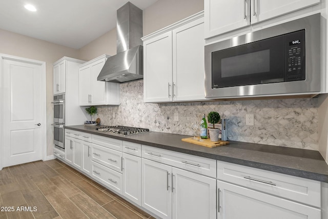 5245 N 205th Ln, Buckeye, AZ 85396 - kitchen featuring wall chimney exhaust hood, stainless steel appliances, dark countertops, white cabinets, and decorative backsplash