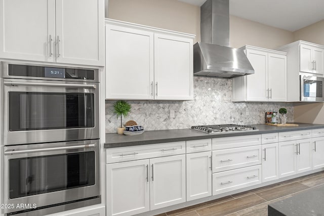 5245 N 205th Ln, Buckeye, AZ 85396 - kitchen featuring wall chimney range hood, dark countertops, stainless steel appliances, and tasteful backsplash