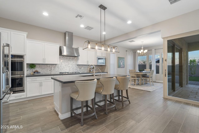 5245 N 205th Ln, Buckeye, AZ 85396 - kitchen featuring a sink, dark countertops, visible vents, appliances with stainless steel finishes, and wall chimney exhaust hood