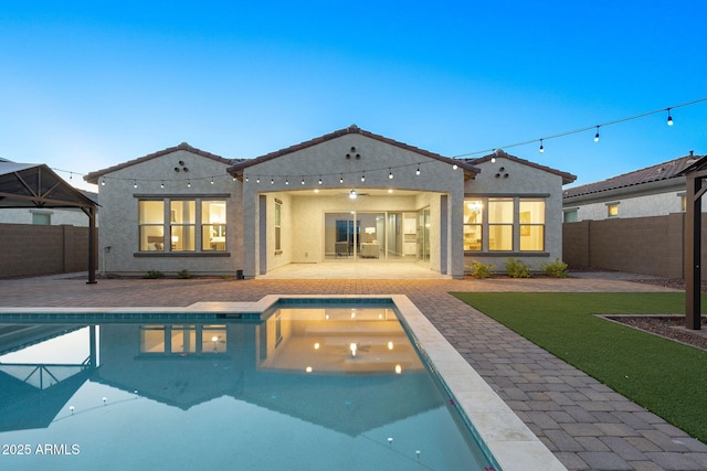 5245 N 205th Ln, Buckeye, AZ 85396 - back of house with stucco siding, a patio, a fenced backyard, a tiled roof, and a fenced in pool