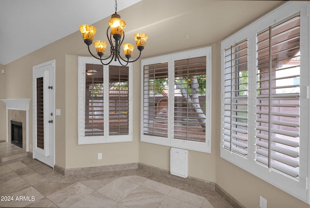 unfurnished dining area featuring a notable chandelier, a tile fireplace, baseboards, and vaulted ceiling