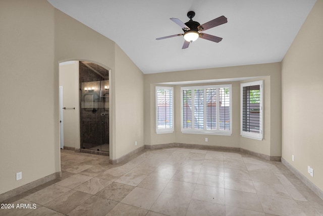 unfurnished room featuring vaulted ceiling, a ceiling fan, arched walkways, and baseboards