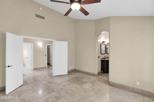 spare room featuring visible vents, baseboards, arched walkways, a ceiling fan, and a sink