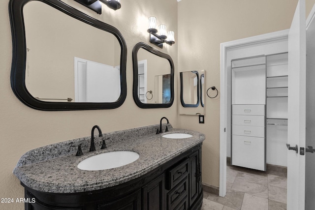 bathroom with double vanity, baseboards, and a sink