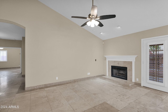 unfurnished living room with a ceiling fan, baseboards, arched walkways, a high end fireplace, and vaulted ceiling