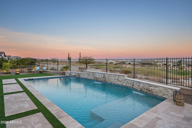 pool at dusk featuring a patio area and pool water feature