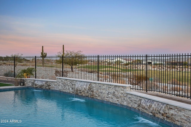 pool at dusk featuring pool water feature