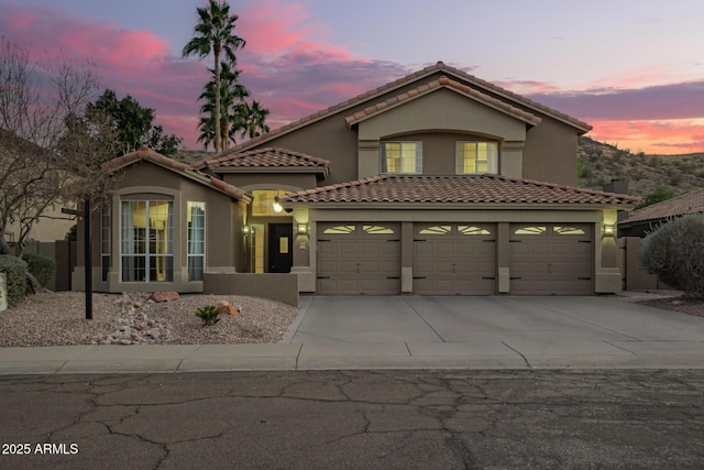 view of front of property featuring concrete driveway, a tiled roof, an attached garage, and stucco siding