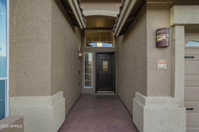 property entrance featuring an attached garage and stucco siding