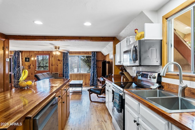 3219 N Pinewood Dr, Pine, AZ 85544 - kitchen featuring appliances with stainless steel finishes, light wood-style flooring, butcher block counters, white cabinetry, and wood walls