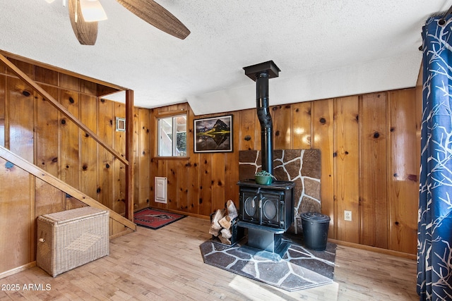 3219 N Pinewood Dr, Pine, AZ 85544 - living area with a wood stove, wood walls, a textured ceiling, wood finished floors, and baseboards