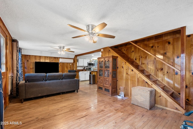 3219 N Pinewood Dr, Pine, AZ 85544 - living room featuring wood walls, ceiling fan, a textured ceiling, light wood-type flooring, and stairway