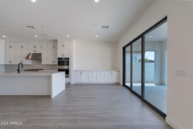 kitchen featuring sink, stainless steel double oven, gas stovetop, tasteful backsplash, and white cabinets