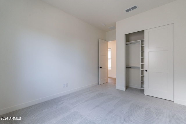 unfurnished bedroom with light carpet and a closet