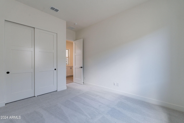 unfurnished bedroom featuring a closet and light colored carpet