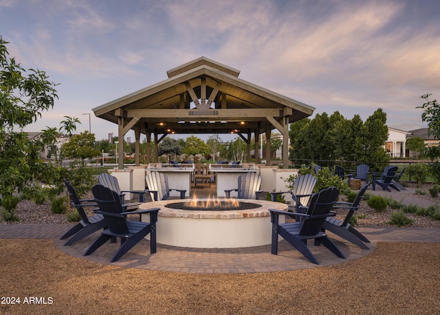 patio terrace at dusk featuring a gazebo, an outdoor bar, and an outdoor fire pit