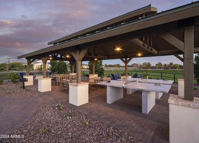 patio terrace at dusk with a gazebo, ceiling fan, and an outdoor bar