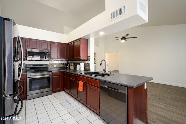 kitchen with backsplash, sink, ceiling fan, kitchen peninsula, and stainless steel appliances